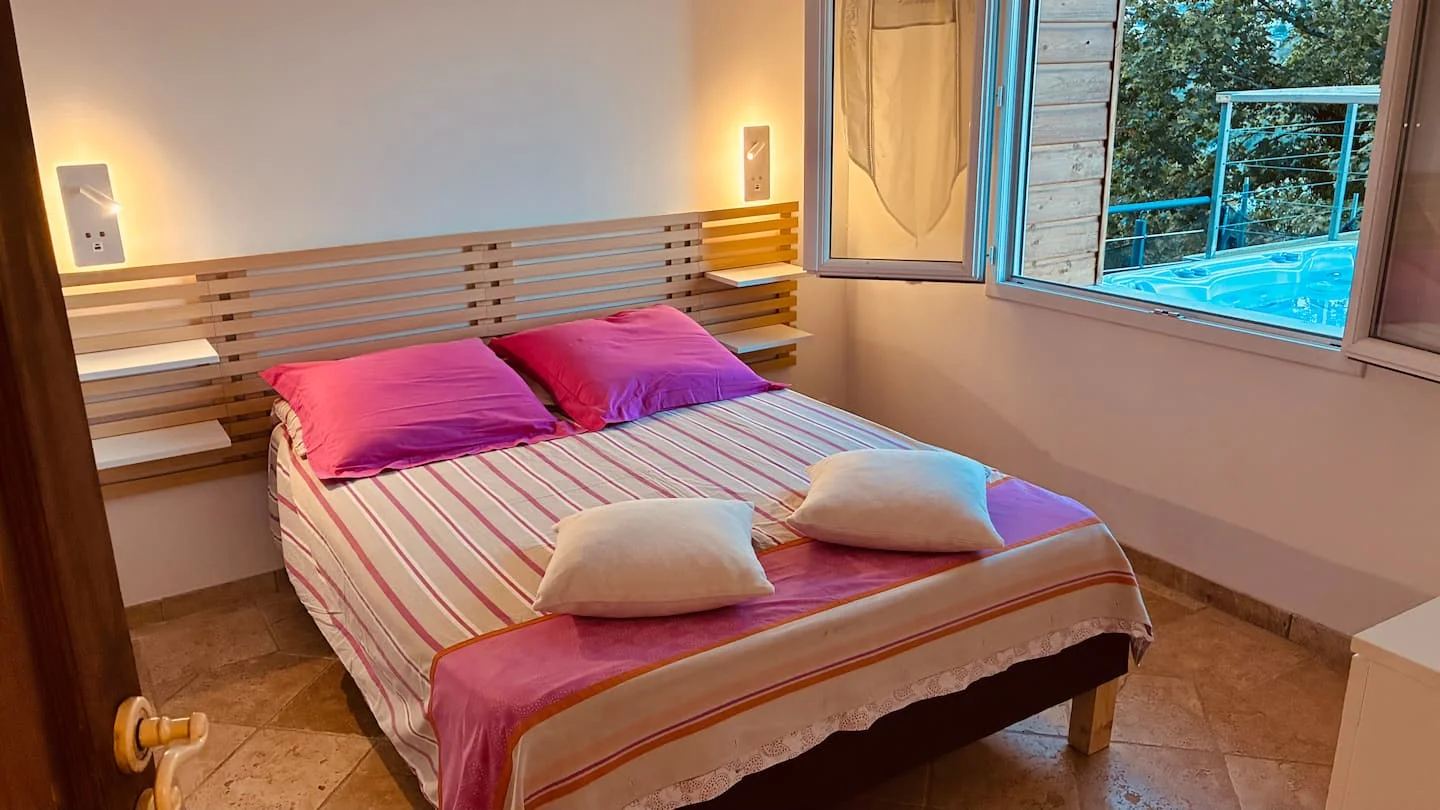 La chambre avec son lit double et une vue sur la terrasse
